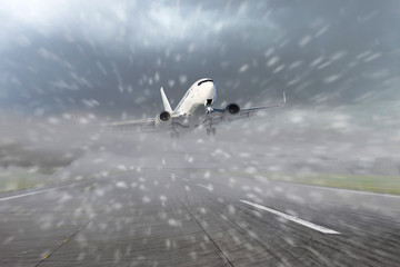 Airliner taking off from the runway at the airport during bad weather, low visibility, snow. Concept of delayed or late flights.
