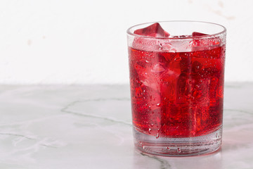 Glass of mango dragonfruit refresher drink on marble table with ice cubes. Copy space.
