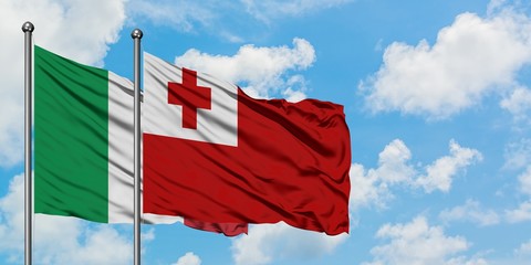 Italy and Tonga flag waving in the wind against white cloudy blue sky together. Diplomacy concept, international relations.