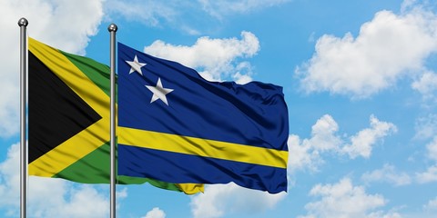 Jamaica and Curacao flag waving in the wind against white cloudy blue sky together. Diplomacy concept, international relations.