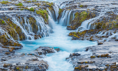 Incredible view of Bruarfoss Waterfall. The 'Iceland’s Bluest Waterfall.' Blue water flows over...