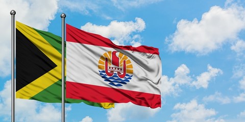 Jamaica and French Polynesia flag waving in the wind against white cloudy blue sky together. Diplomacy concept, international relations.