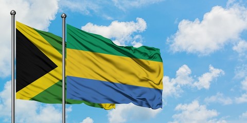 Jamaica and Gabon flag waving in the wind against white cloudy blue sky together. Diplomacy concept, international relations.