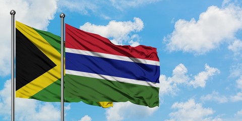 Jamaica and Gambia flag waving in the wind against white cloudy blue sky together. Diplomacy concept, international relations.