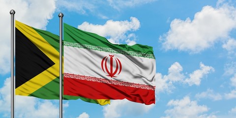Jamaica and Iran flag waving in the wind against white cloudy blue sky together. Diplomacy concept, international relations.