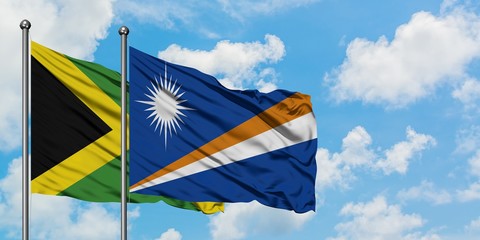 Jamaica and Marshall Islands flag waving in the wind against white cloudy blue sky together. Diplomacy concept, international relations.