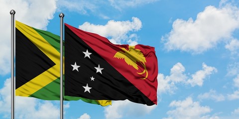 Jamaica and Papua New Guinea flag waving in the wind against white cloudy blue sky together. Diplomacy concept, international relations.
