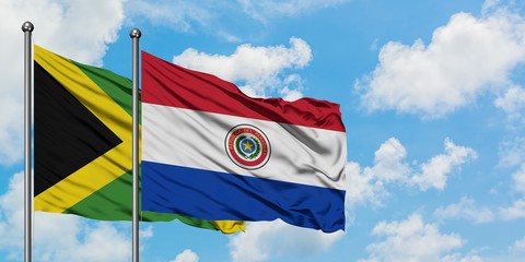 Jamaica and Paraguay flag waving in the wind against white cloudy blue sky together. Diplomacy concept, international relations.