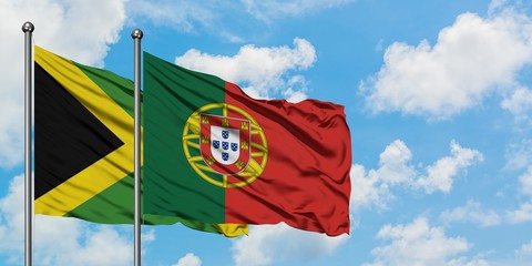 Jamaica and Portugal flag waving in the wind against white cloudy blue sky together. Diplomacy concept, international relations.