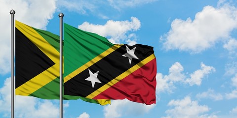 Jamaica and Saint Kitts And Nevis flag waving in the wind against white cloudy blue sky together. Diplomacy concept, international relations.