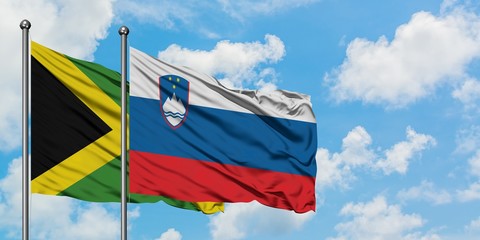 Jamaica and Slovenia flag waving in the wind against white cloudy blue sky together. Diplomacy concept, international relations.