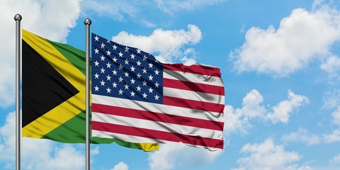 Jamaica and United States flag waving in the wind against white cloudy blue sky together. Diplomacy concept, international relations.