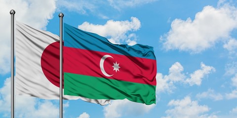 Japan and Azerbaijan flag waving in the wind against white cloudy blue sky together. Diplomacy concept, international relations.