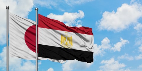 Japan and Egypt flag waving in the wind against white cloudy blue sky together. Diplomacy concept, international relations.