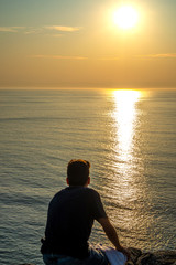 Fototapeta premium young boy relaxed in front of the sea in a sunset, holiday concept