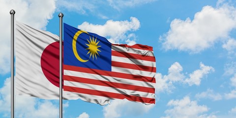 Japan and Malaysia flag waving in the wind against white cloudy blue sky together. Diplomacy concept, international relations.