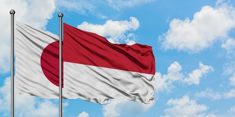 Japan and Monaco flag waving in the wind against white cloudy blue sky together. Diplomacy concept, international relations.