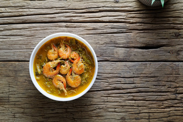 Coconut Milk Curry with young Tamarind Leaves ,morning glory and shrimp in bowl on wood table.Thai traditional food