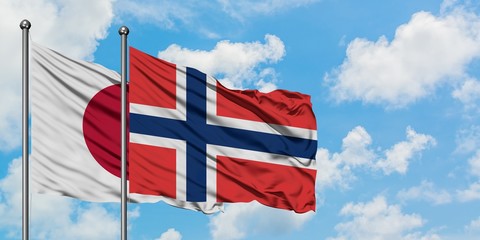 Japan and Norway flag waving in the wind against white cloudy blue sky together. Diplomacy concept, international relations.