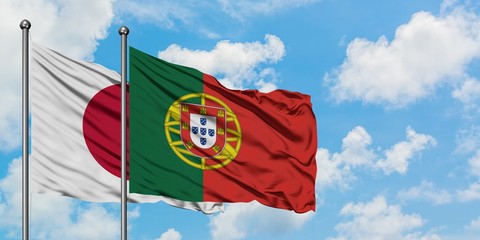 Japan and Portugal flag waving in the wind against white cloudy blue sky together. Diplomacy concept, international relations.