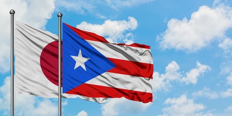 Japan and Puerto Rico flag waving in the wind against white cloudy blue sky together. Diplomacy concept, international relations.