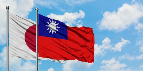 Japan and Taiwan flag waving in the wind against white cloudy blue sky together. Diplomacy concept, international relations.