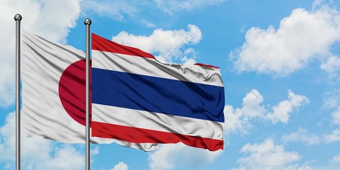 Japan and Thailand flag waving in the wind against white cloudy blue sky together. Diplomacy concept, international relations.