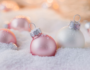 Silver and pink Christmas balls on snowy background, toned