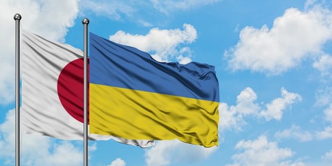 Japan and Ukraine flag waving in the wind against white cloudy blue sky together. Diplomacy concept, international relations.