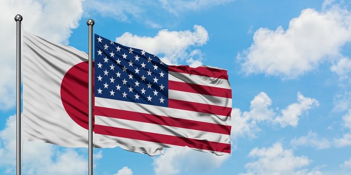 Japan and United States flag waving in the wind against white cloudy blue sky together. Diplomacy concept, international relations.