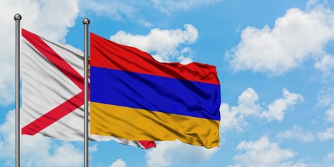 Jersey and Armenia flag waving in the wind against white cloudy blue sky together. Diplomacy concept, international relations.