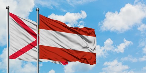 Jersey and Austria flag waving in the wind against white cloudy blue sky together. Diplomacy concept, international relations.