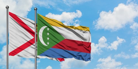 Jersey and Comoros flag waving in the wind against white cloudy blue sky together. Diplomacy concept, international relations.