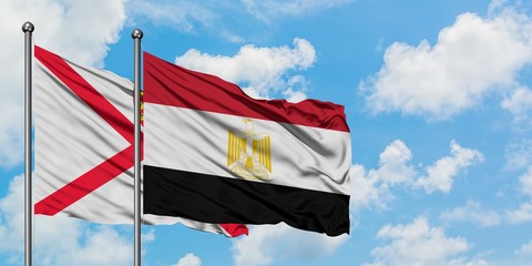 Jersey and Egypt flag waving in the wind against white cloudy blue sky together. Diplomacy concept, international relations.