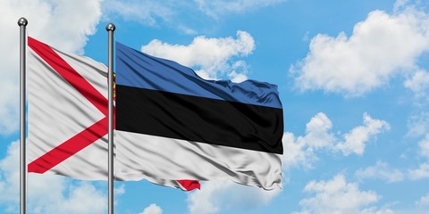 Jersey and Estonia flag waving in the wind against white cloudy blue sky together. Diplomacy concept, international relations.