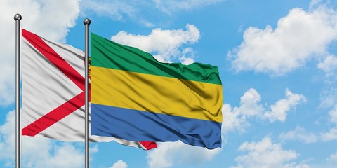 Jersey and Gabon flag waving in the wind against white cloudy blue sky together. Diplomacy concept, international relations.