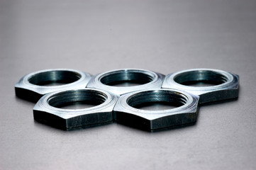 Five chrome metal nuts in the shape of honeycombs