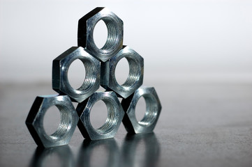 Close-up of a pyramid of five chrome metal nuts