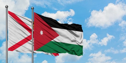 Jersey and Jordan flag waving in the wind against white cloudy blue sky together. Diplomacy concept, international relations.