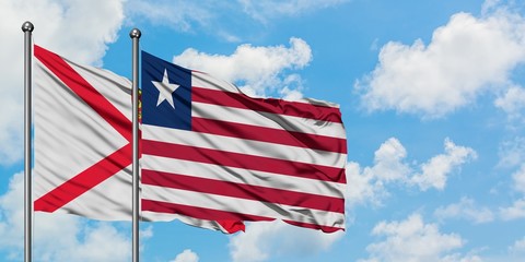 Jersey and Liberia flag waving in the wind against white cloudy blue sky together. Diplomacy concept, international relations.