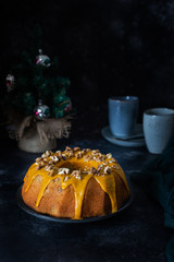 Bundt cake, orange cake with walnuts and yellow sugar icing with turmeric spice. Dark background