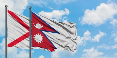Jersey and Nepal flag waving in the wind against white cloudy blue sky together. Diplomacy concept, international relations.