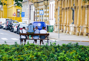 Fototapeta na wymiar Zagreb/Croatia - August 27th 2019. Four friends relaxing on a bench on roadside in Zagreb, Croatia. European destination. Very nice capital city of Croatia. Central park.