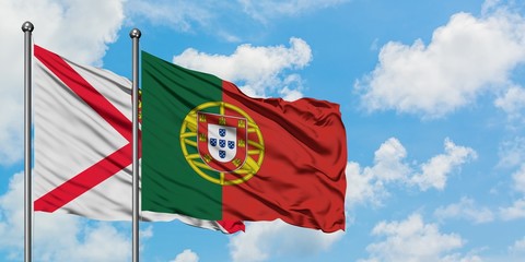 Jersey and Portugal flag waving in the wind against white cloudy blue sky together. Diplomacy concept, international relations.
