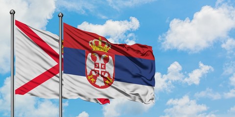 Jersey and Serbia flag waving in the wind against white cloudy blue sky together. Diplomacy concept, international relations.