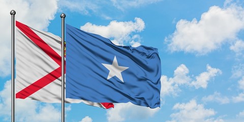 Jersey and Somalia flag waving in the wind against white cloudy blue sky together. Diplomacy concept, international relations.