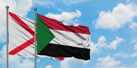 Jersey and Sudan flag waving in the wind against white cloudy blue sky together. Diplomacy concept, international relations.