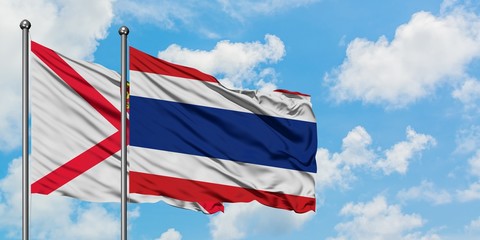 Jersey and Thailand flag waving in the wind against white cloudy blue sky together. Diplomacy concept, international relations.