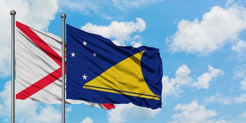 Jersey and Tokelau flag waving in the wind against white cloudy blue sky together. Diplomacy concept, international relations.