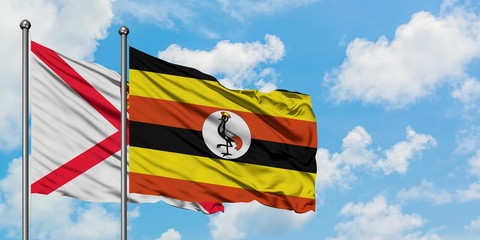 Jersey and Uganda flag waving in the wind against white cloudy blue sky together. Diplomacy concept, international relations.